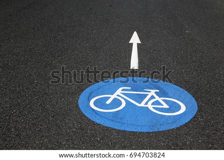 Bicyle sign on blue ground painted onto the asphalt of a suburban street