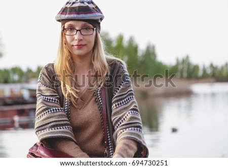 blonde with long hair sitting on the beach and looking straight autumn day
