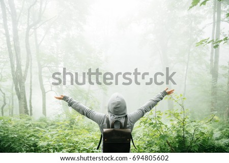 Freedom traveler stood with his arms raised and enjoying the beautiful nature with fog. Royalty-Free Stock Photo #694805602