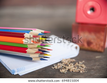 Color pencils with sharpener and shavings on the wood table.