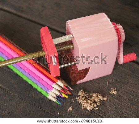Color pencils with sharpener and shavings on the wood table.