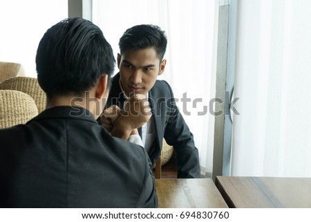 Two asian businessman are clash arm wrestle on brown table in office