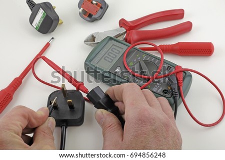 Earth continuity testing – An electrician testing a mains cable earth with a multimeter  Royalty-Free Stock Photo #694856248
