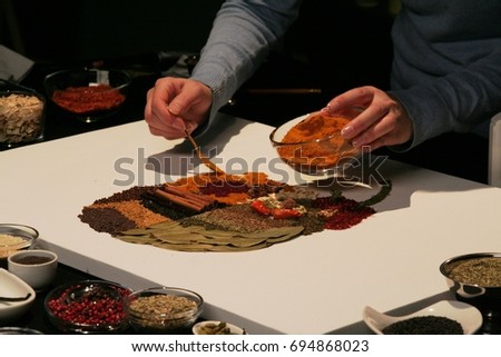 The picture made of spices, spicy art, hands with pot and spoon