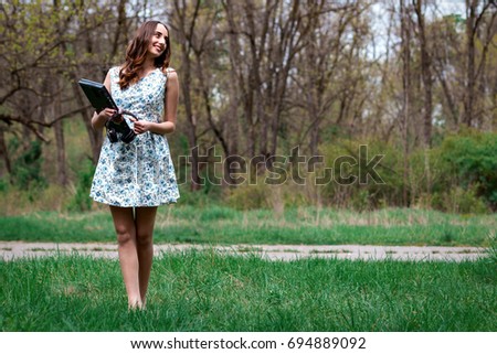 Woman or girl in a dress, with laptop and headphones happy in the park