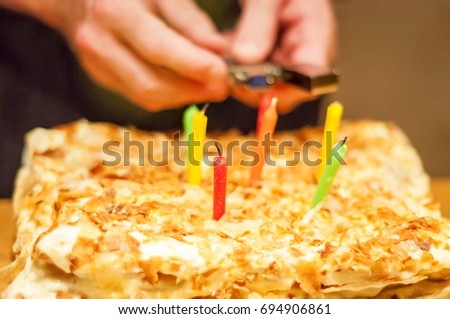 Person lighting candles on a Napoleon birthday cake, surprise party stock image.