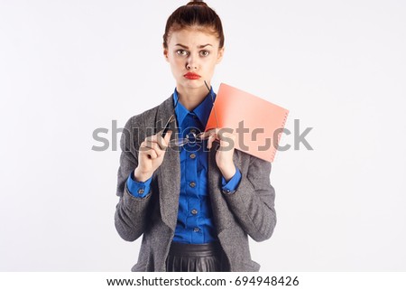 Young beautiful woman holds notebook and glasses, teacher on white isolated background.
