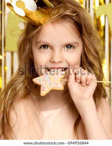 Little girl kid hold ginger candy lollipops on birthday party happy smiling on gold background