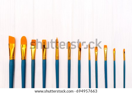 Top view of brushes on the white wooden background. Set of brushes