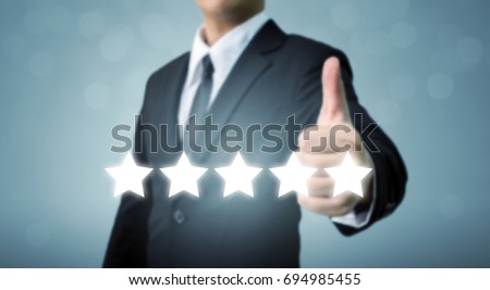 Businessman showing hand sign thumb up and five star symbol to increase rating of company, The excellence of the business or service concept Royalty-Free Stock Photo #694985455