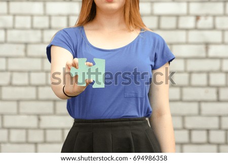 Female student concept. Beautiful girl near a brick wall. Holds a puzzle in his hand. education system . Photo for your design