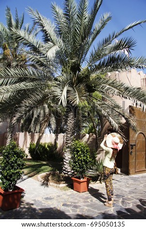 A lady tourist  taking a picture for a date palm tree in the Heritage Village at Abu Dhabi
