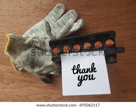 Concept image of dirty hand glove/old battery and sticky noted word - Thank you on the plywood table.Selective focus.