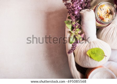 Massage setting with herbal compress balls ,fresh herbs and flowers and bathroom salts  on light background,top view. Healthy Lifestyle or Spa and wellness concept Royalty-Free Stock Photo #695085568