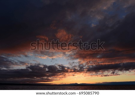 Red shades of sunlight in a gloomy cloudy sky at sunset