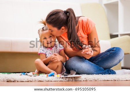Mother and daughter in their home. They are playing with plasticine.