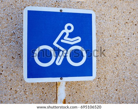 Bicycle lane blue and white sign by a wall