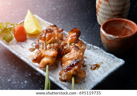 Japanese chicken grill or yakitori serve in izakaya style restourant set on Japanese style dish with flash lighting.