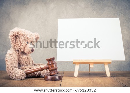Teddy bear toy with auction gavel and easel for painting with canvas blank front concrete wall background. Retro instagram old style filtered photo