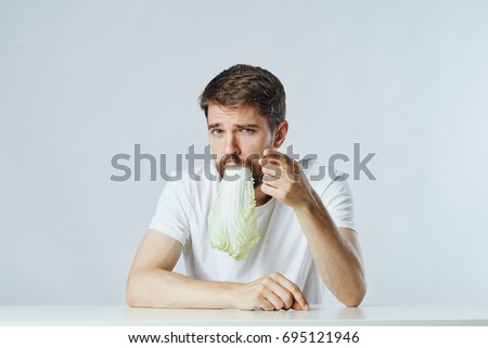 Man eating lettuce leaves on gray background                               