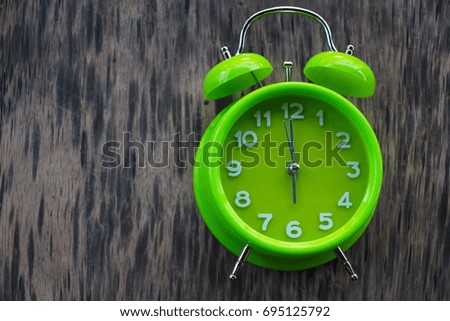 Conceptual Image : Green table clock on the old wooden table, The time is precious, selective focus