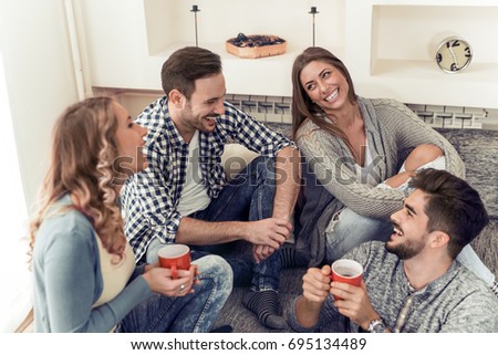 Group of friends talking and having fun while sitting on the couch.They are meet at friend's home for a coffee break.