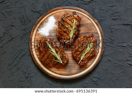 Barbecue Entrecote Steaks on a round cutting board on a stone table