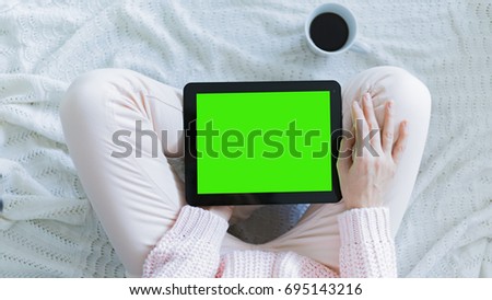 Woman at home relaxing reading on the tablet computer with pre-keyed green screen