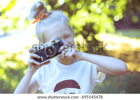 little pretty girl with retro camera outdoor
