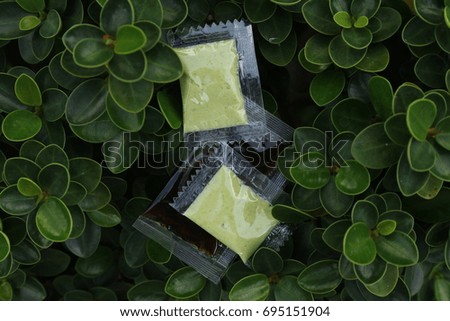 Soy sauce and wasabi in plastic package in nature green leaves  background, ingredients