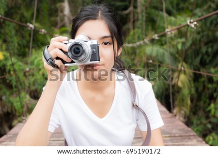 Beautiful young asian woman taking photos outdoors in a forest