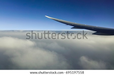 Looking through window aircraft during flight. Flying over the blue sky with clouds.