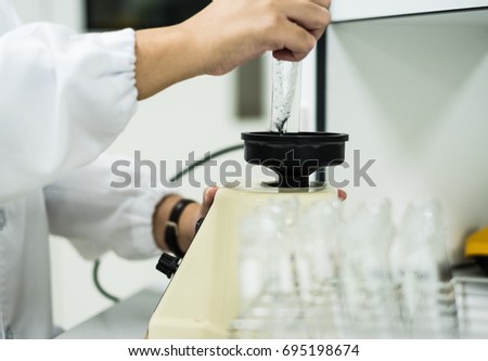 The chemist mixing the mixture of test solution by press the test tube on the rubber cup of mixer machine, concept of general and pharmaceutical laboratory.Selective focus photography.
