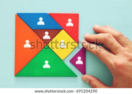 image of tangram  puzzle blocks with people icons over wooden table ,human resources and management concept. Royalty-Free Stock Photo #695204290
