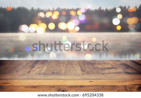 vintage wooden board table in front of abstract photo of misty and foggy lake at morning/evening. For product display and presentation