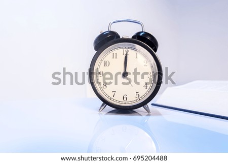 Vintage alarm clock and book with reflection ideal for exam, time is money and relaxing concept
