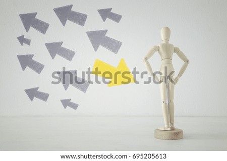 image of wooden person standing with his back in front of textured background full of arrows pointing in different directions. decision and strategy plan concept