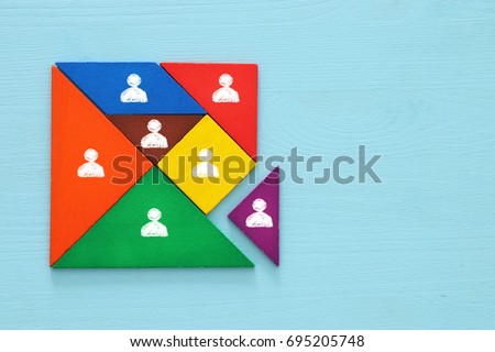 image of tangram puzzle blocks with people icons over wooden table ,human resources and management concept.