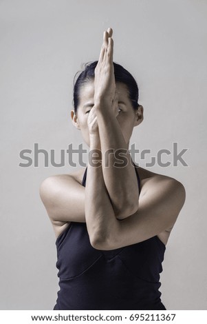 Portrait of mid Asian woman is playing yoga in studio in black sport wear

