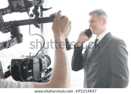 Videographer using steadycam, making video of businessman talking on phone