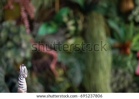 Miniature craft of wooden zebra with abstract blur of jungle for background, copy space for your text. Wildlife and animal preservation concept. Soft focus