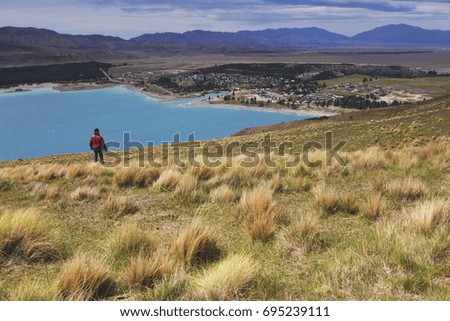 A man standing looking at small town below the hill.