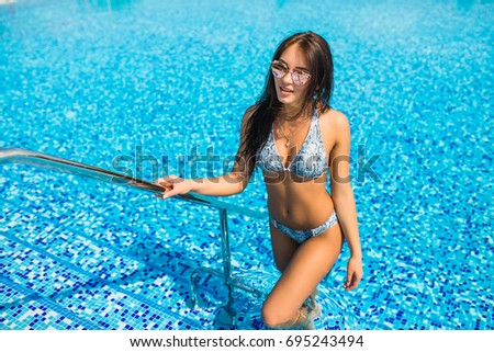 Girl standing in pool and enjoying the summer time