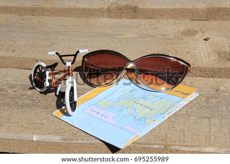 The concept of cycling: a model of a bicycle, a paper map, sunglasses on a wooden forte. Cycling, traveling
