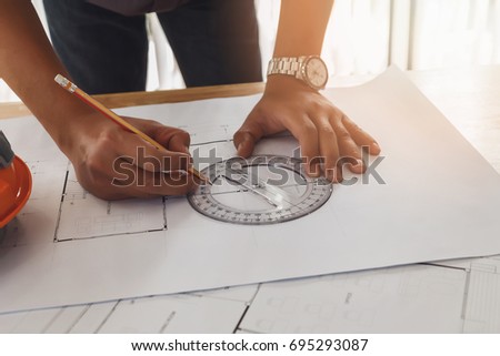 Architect or engineer using pencil and protractor working on blueprint, architectural concept