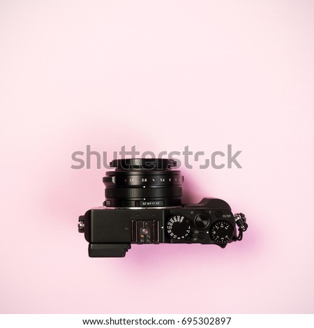 Vintage digital compact camera on pink pastel color background with flat layout and copy space for design work
