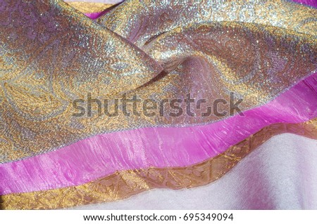 Texture, background, pattern. Combined silk white fabric and gold and silver damask fabric, pink ribbons