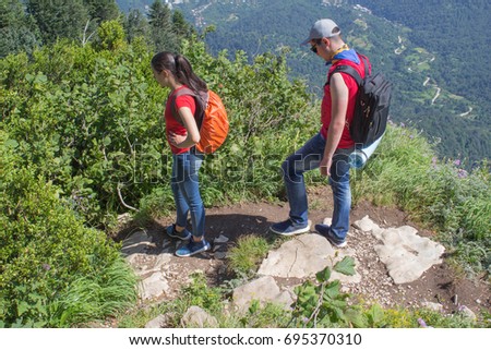 Traveler travel on the artificial roadway of the mountains reserve. Active hikers. Active and healthy lifestyle on summer vacation and weekend tour. Two young Tourists With Backpacks travel