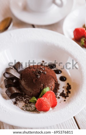 Chocolate fondant on white plate with decoration from strawberry and mint. Delicious dessert serving in restaurant, close up picture