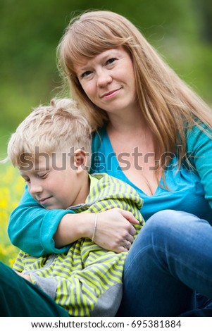 Mom and young nine years old son resting together in summer park, close up portrait